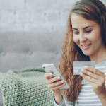 Frau überprüft Zahlung mit Smartphone und Bankkarte – Symbolbild für Empfängerüberprüfung bei Online-Überweisungen.